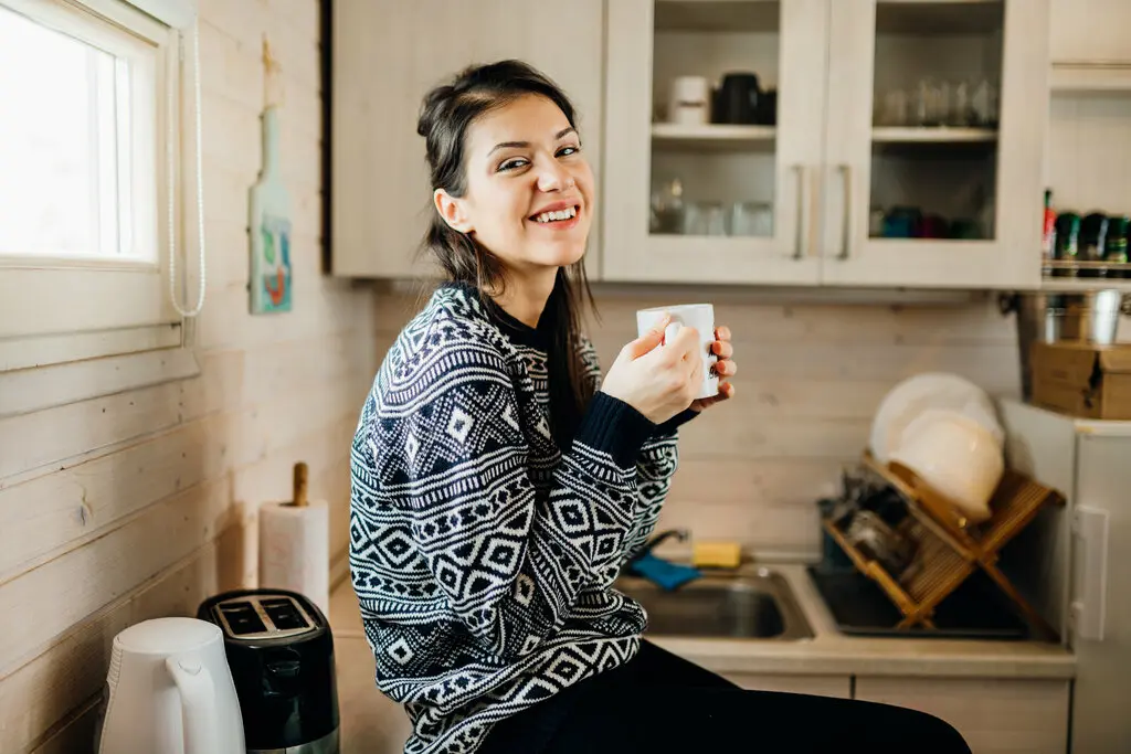 tiny-house-kleines-haus-wohnung-wohnen-010 Glückliche Frau in einer kleinen Küche.